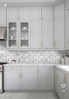 a kitchen with white cabinets and gold trim