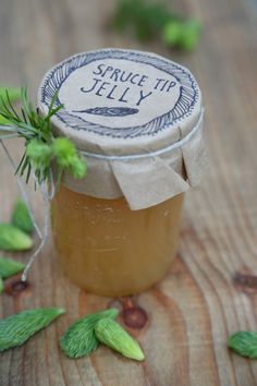 a jar filled with honey sitting on top of a wooden table next to green leaves