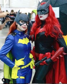 two women dressed up as batman and catwoman pose for a photo in front of a crowd