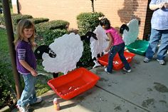 three children are playing with paper mache sheep