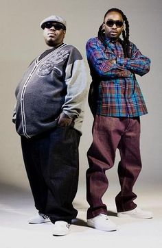 two men standing next to each other in front of a white background with their arms crossed