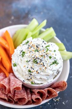 a plate with carrots, celery, meat and dip