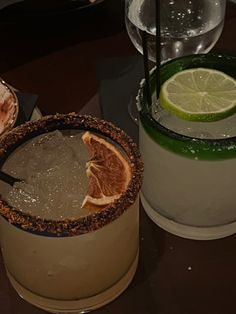 two glasses filled with drinks sitting on top of a table