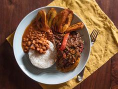 a white plate topped with meat, beans and rice