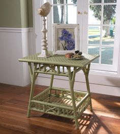 a green table sitting in the middle of a room next to a window with shutters