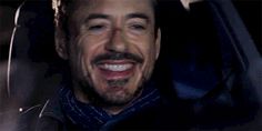 a man with a goatee smiles while sitting in a car