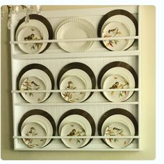 plates are arranged on a white shelf with brown trim around the edges and below them