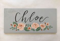 a wooden sign with flowers on it that says cloee and the word cloe written in cursive writing