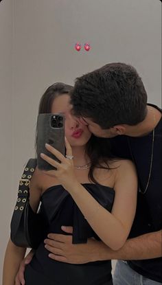 a man and woman taking a selfie in front of a mirror with their cell phone