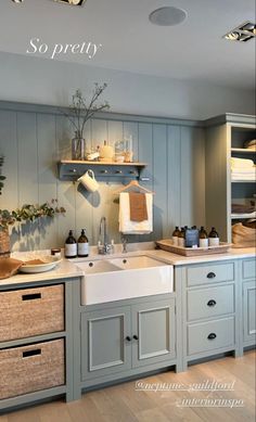 a kitchen with gray cabinets and white sink in the center is filled with items that are on shelves