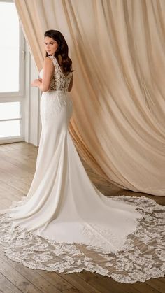 a woman standing in front of a curtain wearing a wedding dress with an open back