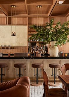 a bar with stools and tables in front of it, along with a potted plant