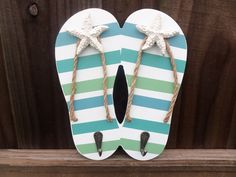 "Stripe Sandals Hook Plaque, Flip Flop Wall Hook Decor,  2 Hooks Flip Flops These are hand painted white with ocean colored stripes, jute rope straps and two metal hooks (1 1/4\" Long) fixed to the bottom with screws. The back has a key hole for easy way to hang on the wall. You can use this for hand towels, keys, dog leash etc. Measures 8 1/4\" Tall by 7\" Wide  Looks great in a Patio, Tiki bar setting, bathroom, nautical man cave, home bar, porch, deck, game room... anywhere you want an extra Wood Flip Flop Door Hangers, Beach T-strap Flip Flops With Cushioned Footbed, T-strap Flip Flops For Beach Vacation, Handmade Slip-on Flip Flops For Beach, Cheap Summer T-strap Flip Flops, Coastal Bathroom Decor, Flip Flop Craft, Beach Flip Flops, Synthetic Material, Ocean Colors