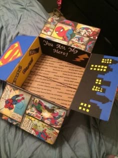 an open box on top of a bed covered in paper and magnets with superman logos