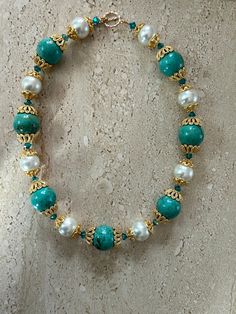 Turquoise Necklace features 20MM round stabiles turquoise stones and white shell pearl beads accented with gold over copper Bali style bead caps and Swarovski crystals.  Toggle clasp.  Necklace measures 18 inches. GIFT BOXED Elegant Turquoise Necklace With Spacer Beads, Turquoise Pearl Jewelry With Round Beads, Elegant Turquoise Beaded Necklaces With Spacer Beads, Elegant Turquoise Beaded Necklace With Spacer Beads, Elegant Turquoise Jewelry With Spacer Beads, Handmade Turquoise Pearl Necklace With Round Beads, Handmade Turquoise Pearl Necklace, Handmade Turquoise Pearl Beaded Necklaces, Handmade Turquoise Pearl Beaded Necklace