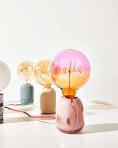 a pink lamp with the word hello on it sitting next to other lamps and lights