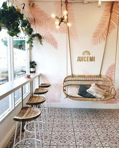 the interior of a restaurant with hanging chairs and plants on the wall behind them,