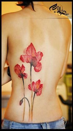 a woman's lower back tattoo with red flowers