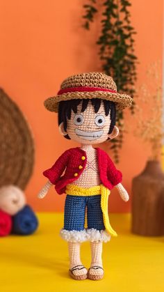 a small doll is wearing a red shirt and blue pants with a straw hat on