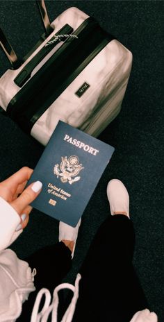 a person is holding a passport in front of a suitcase and another piece of luggage