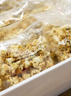 two bags of popcorn sitting on top of a white tray next to each other in plastic wrappers