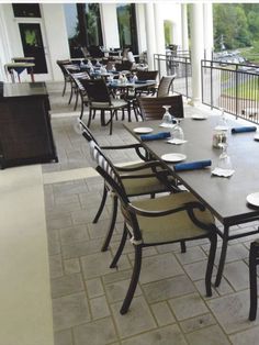 an outdoor dining area with tables, chairs and plates on the outside patio overlooking a lake