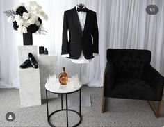 a black tuxedo suit sitting on top of a table next to a chair