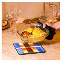 a bowl filled with food sitting on top of a table next to wine glasses and place mats