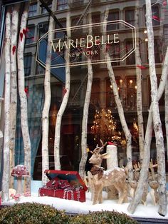 a store window with fake trees and deer statues