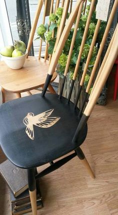 a wooden chair sitting on top of a hard wood floor next to a potted plant