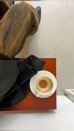 a cup of coffee sitting on top of a wooden table