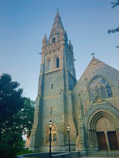 an old church with a clock tower on it's side and street lights in front