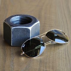 a pair of sunglasses sitting on top of a wooden table next to a metal object