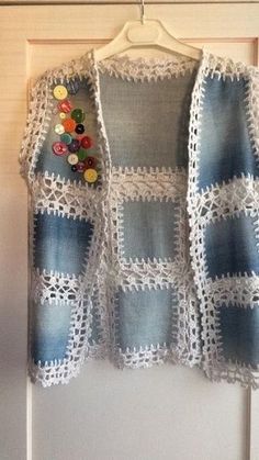 a crocheted jacket hanging on a door with buttons attached to the back of it