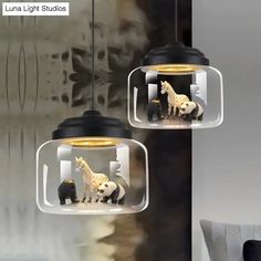 two glass pendant lights with animals in them