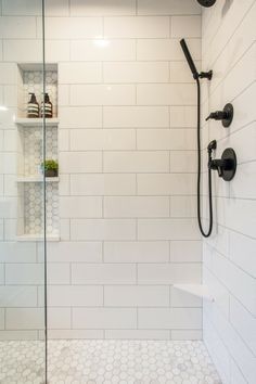 a walk in shower sitting next to a white tiled wall and floor with hexagonal tiles on the walls