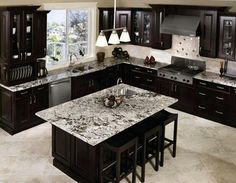 a kitchen with marble counter tops and dark wood cabinets