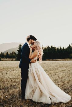 a bride and groom kissing in an open field