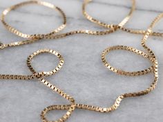 This classic box chain necklace is crafted from highly polished gold. Each link creates a fluid play of light that almost seems to sparkle when worn. This is a versatile piece that would look lovely worn alone or strung with a pendant. Metal: 14K Yellow Gold Width of Chain: 1.4 mm Length of Chain: 23 Inches Marks: "BVL 14K" Stamped on the clasp Box Chain Necklace, Gold Chain With Pendant, Basic Jewelry, Right Hand Rings, Layered Chains, Gold Box, Necklace Box, Yellow Gold Chain, Chain Gold