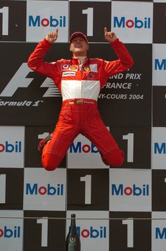 a man is jumping in the air on top of a race podium with his hands up