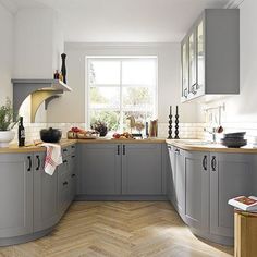 a kitchen with grey cabinets and wooden floors