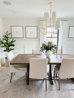 a dining room table with white chairs and a potted plant in the middle of it