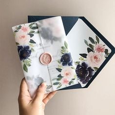 a person holding three envelopes with flowers on them and a penny in the middle