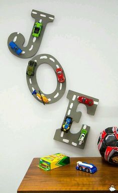 a wooden table topped with toy cars next to a wall mounted sign that says joy