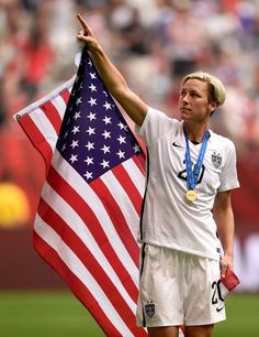 a female soccer player holding an american flag