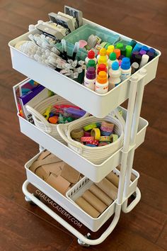 a white cart filled with lots of crafting supplies on top of a wooden floor