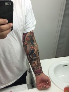 a man with a tattoo on his arm taking a selfie in front of a mirror