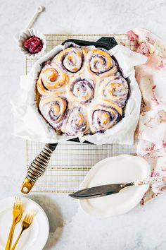 a table topped with a cake covered in icing next to plates and utensils