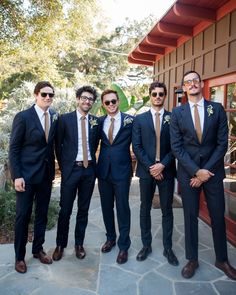 a group of men standing next to each other wearing suits and ties with sunglasses on