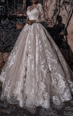 a woman wearing a wedding dress standing in front of a wall with graffiti on it